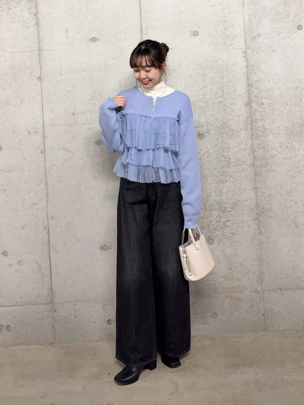 ブルー系のニット/セーター、ブラック系のデニムパンツ、ブラック系のブーツを着用したレディースの秋コーディネートの2枚目の写真