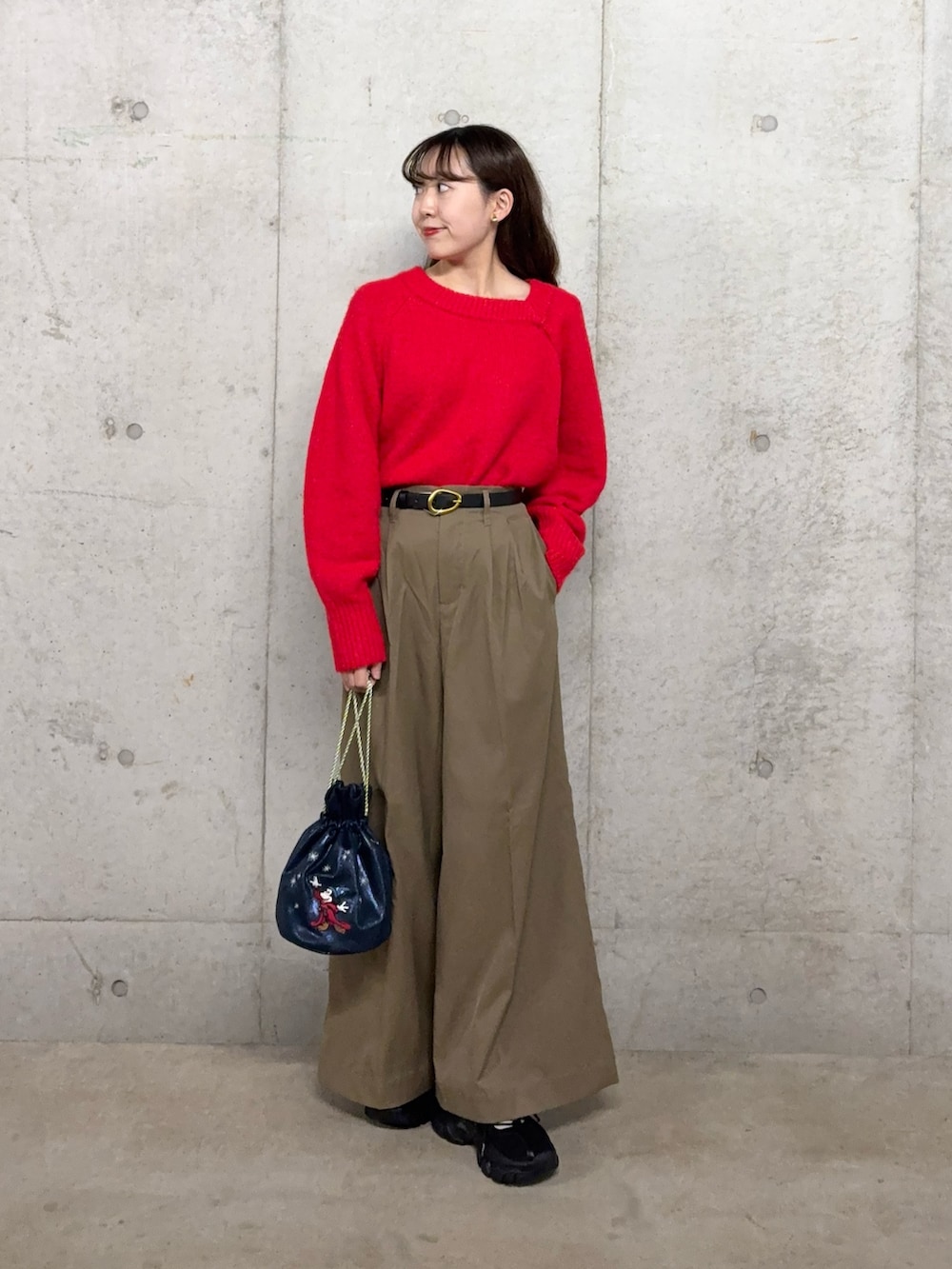 レッド系のニット/セーター、ベージュ系のチノパンツ、ブルー系のショルダーバッグを着用したレディースの冬コーディネートの2枚目の写真