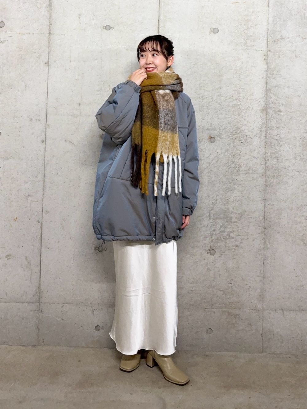 ブラウン系のニット/セーター、ホワイト系のスカート、グリーン系のダウンジャケット/コートを着用したレディースの秋コーディネートの2枚目の写真