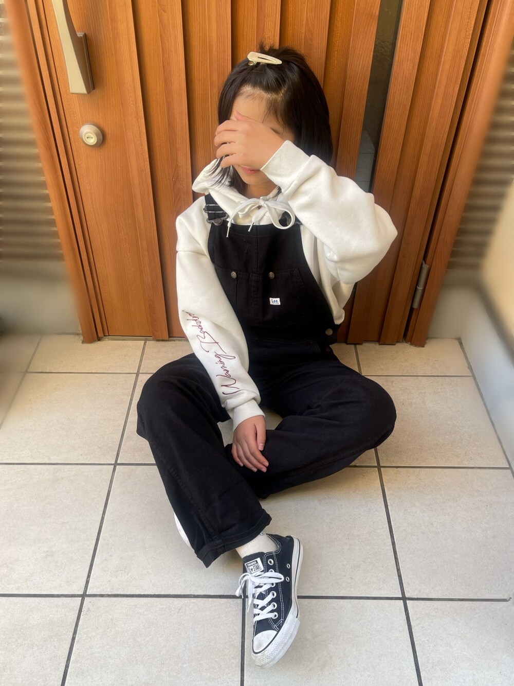 ホワイト系のパーカー、ブラック系のサロペット/オーバーオール、ブラック系のシューズを着用したキッズの冬コーディネートの2枚目の写真