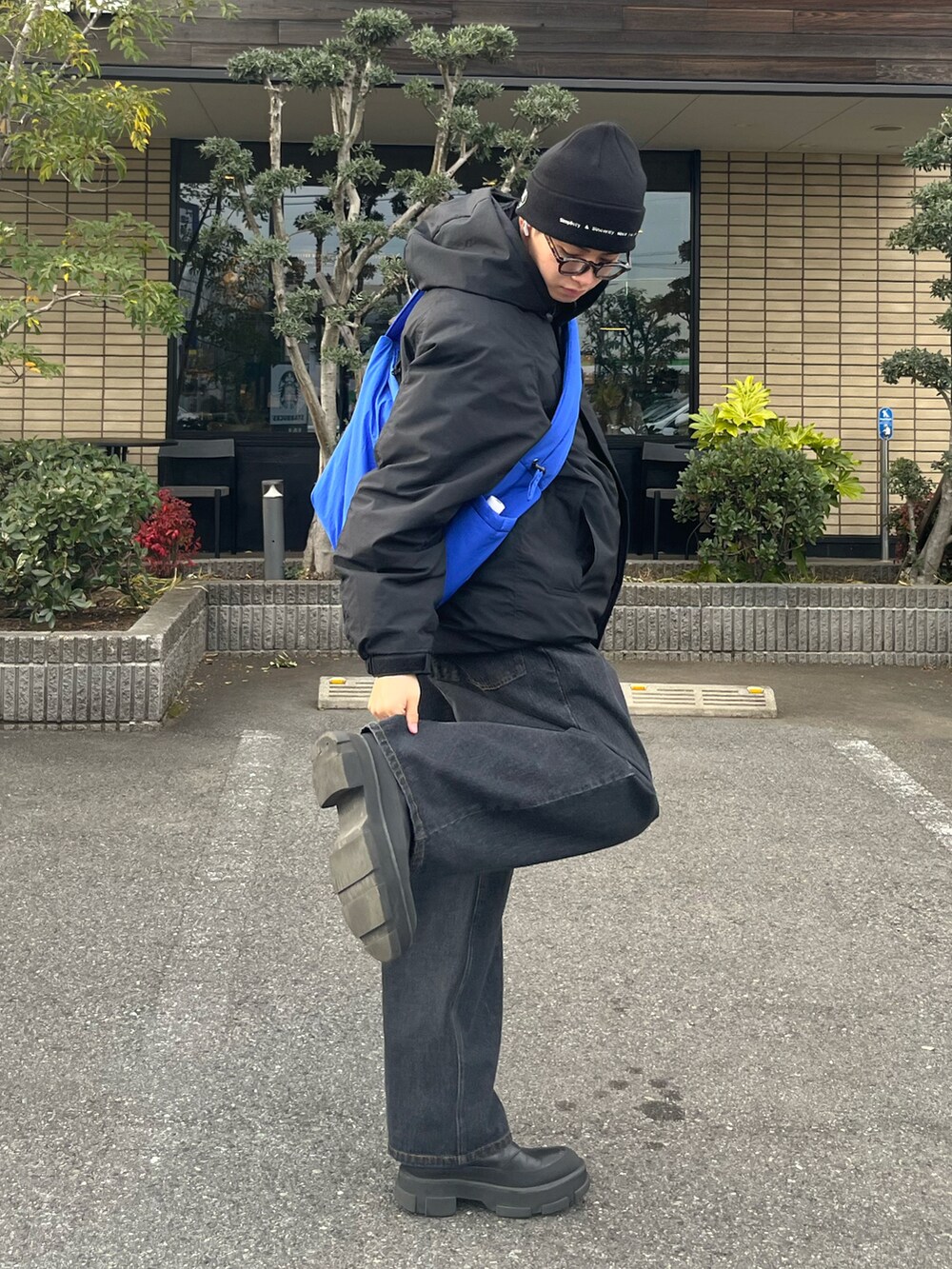 ブルー系のベスト、ブルー系のデニムパンツ、ブルー系のショルダーバッグを着用したメンズの冬コーディネートの2枚目の写真