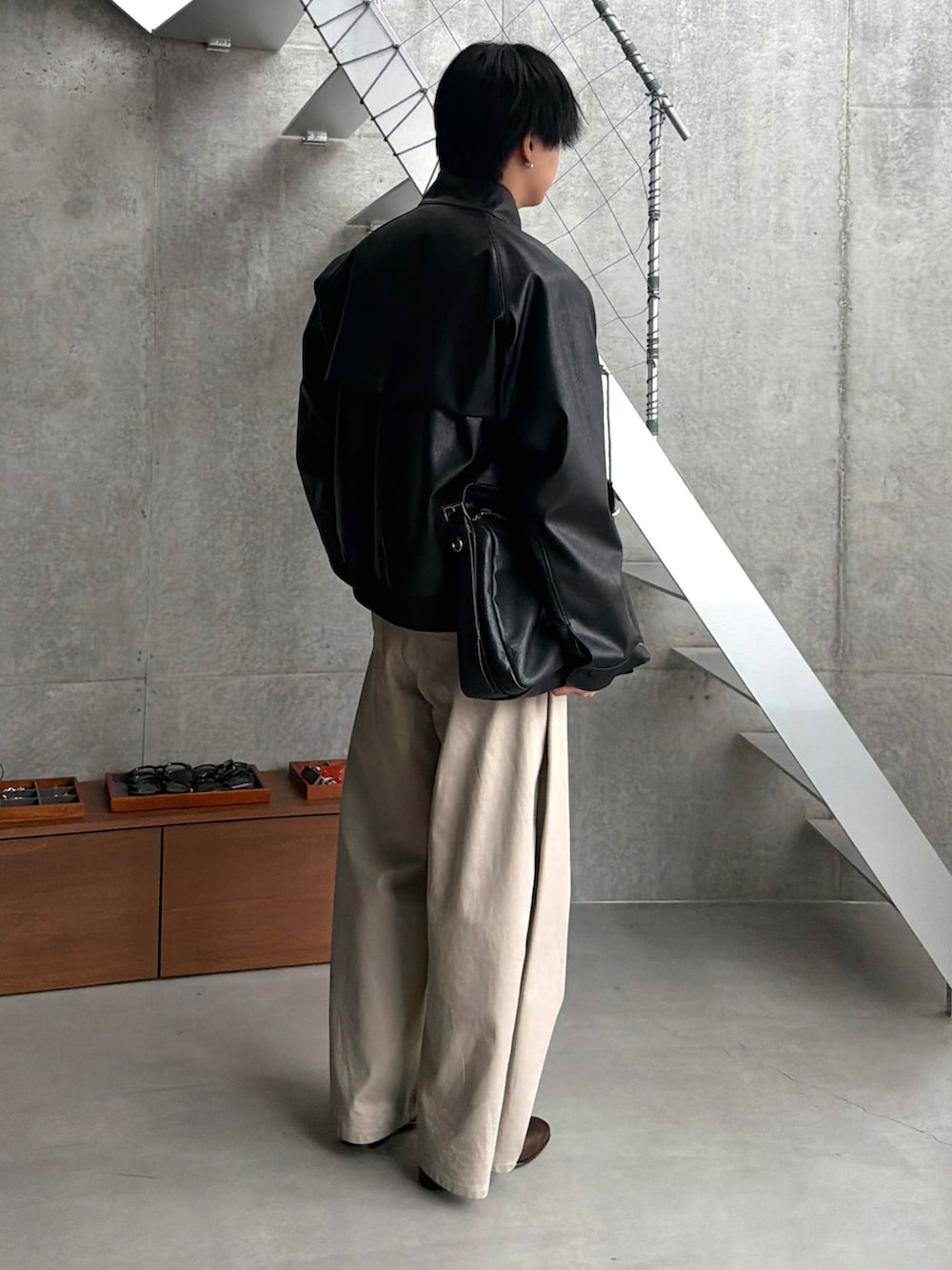 レッド系のニット/セーター、ブラック系のブルゾン、ベージュ系のデニムパンツを着用したメンズの秋コーディネートの2枚目の写真