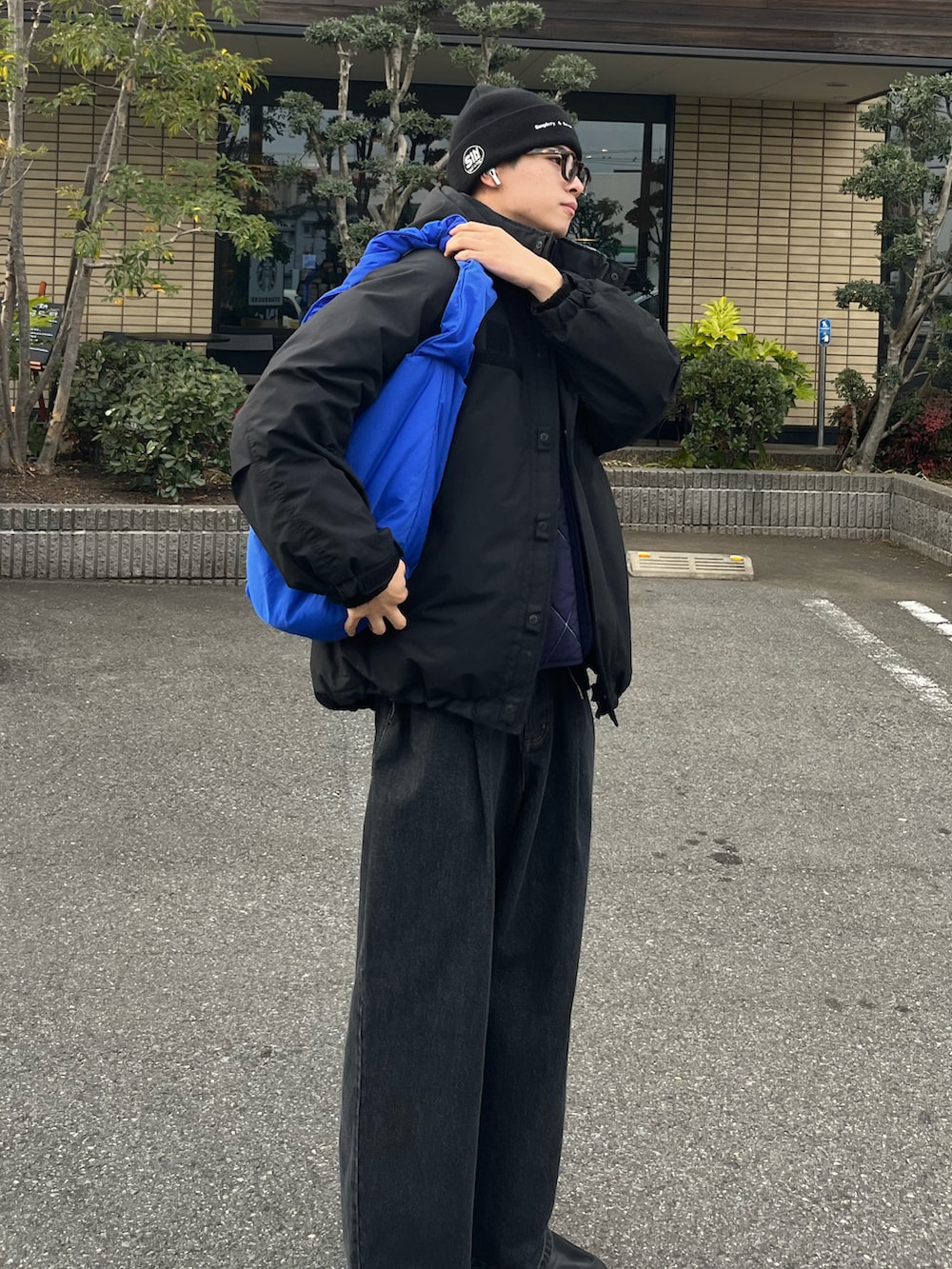 ブルー系のベスト、ブルー系のデニムパンツ、ブルー系のショルダーバッグを着用したメンズの冬コーディネートの3枚目の写真