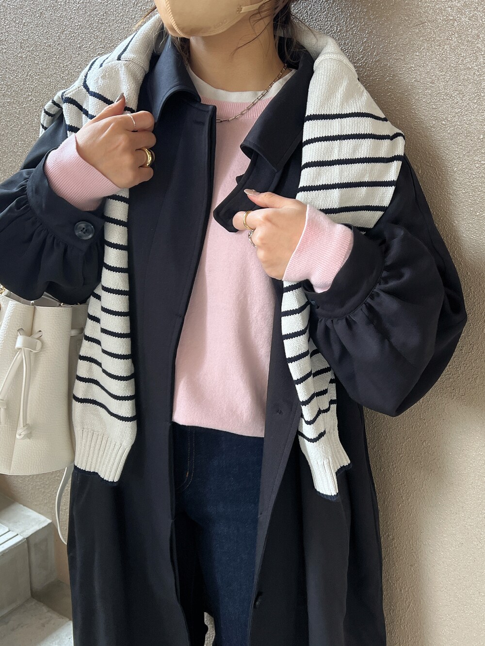 ブルー系のデニムパンツ、ホワイト系のスニーカー、ブラック系のステンカラーコートを着用したレディースの冬コーディネートの2枚目の写真