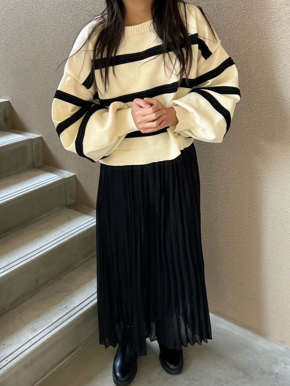 ブラック系のスカート、ブラック系のブーツ、ホワイト系のニット/セーターを着用したレディースの冬コーディネートの2枚目の写真