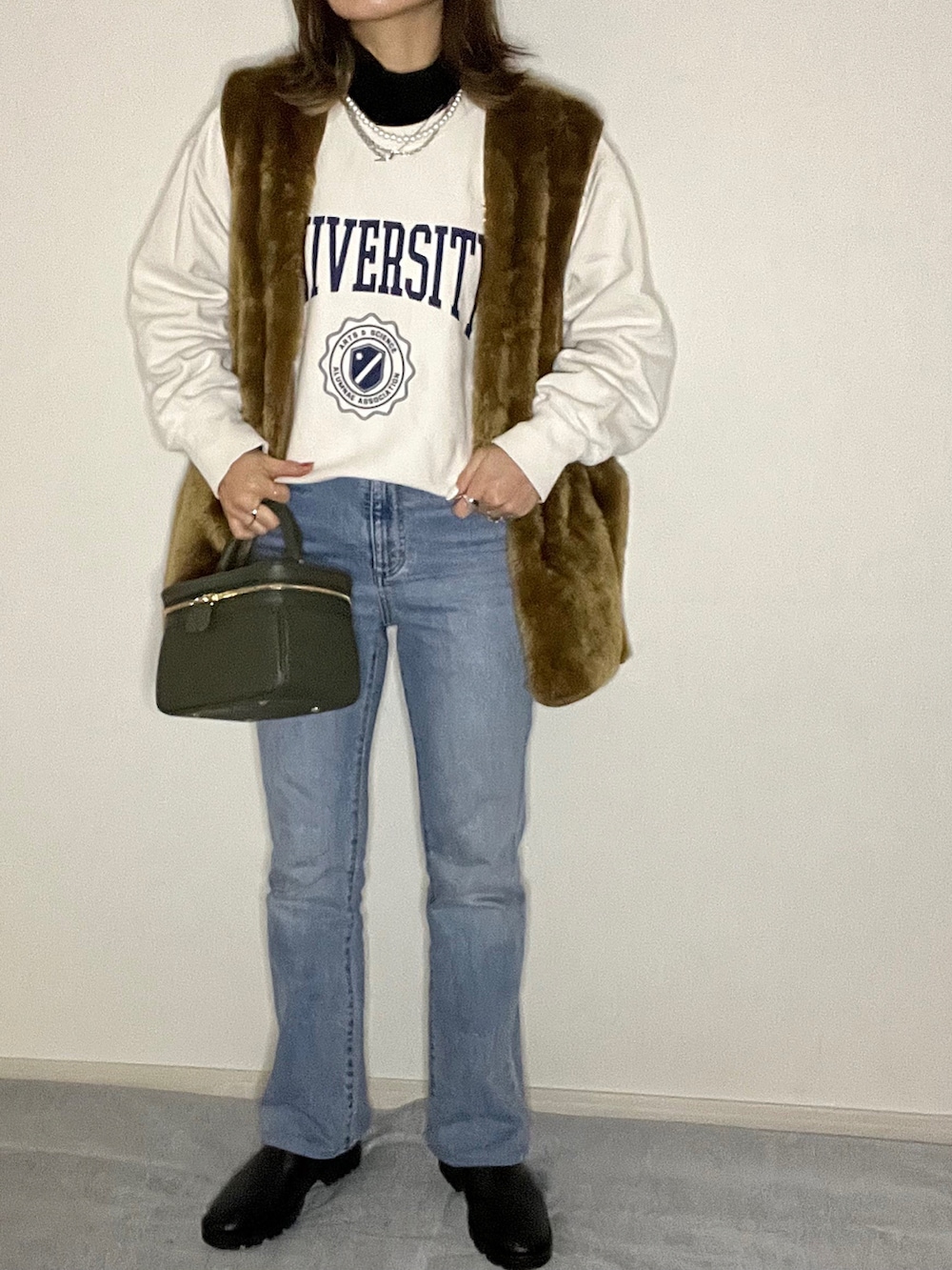 グリーン系のバッグ、ブルー系のデニムパンツ、ブラック系のブーツを着用したレディースの冬コーディネートの2枚目の写真