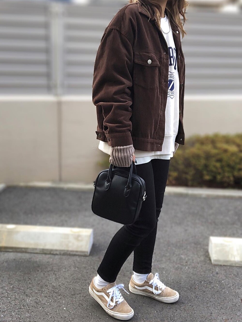 ブラック系のハンドバッグ、ホワイト系のスウェット、ブラック系のデニムパンツを着用したレディースの冬コーディネートの2枚目の写真