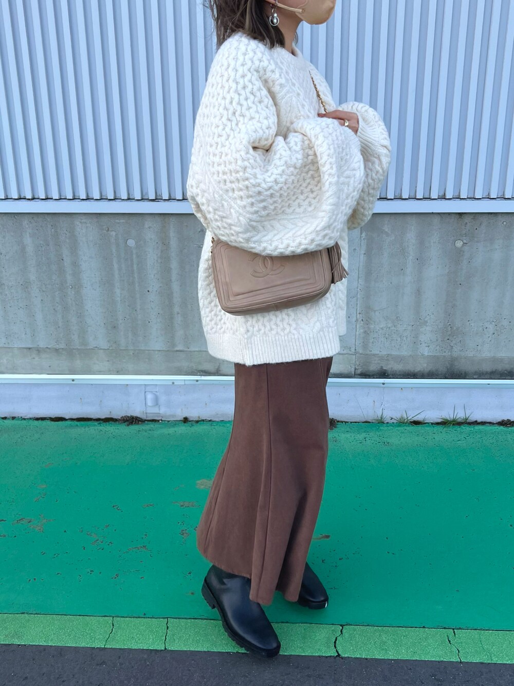 ホワイト系のニット/セーター、ブラウン系のスカート、ブラック系のブーツを着用したレディースの冬コーディネートの3枚目の写真