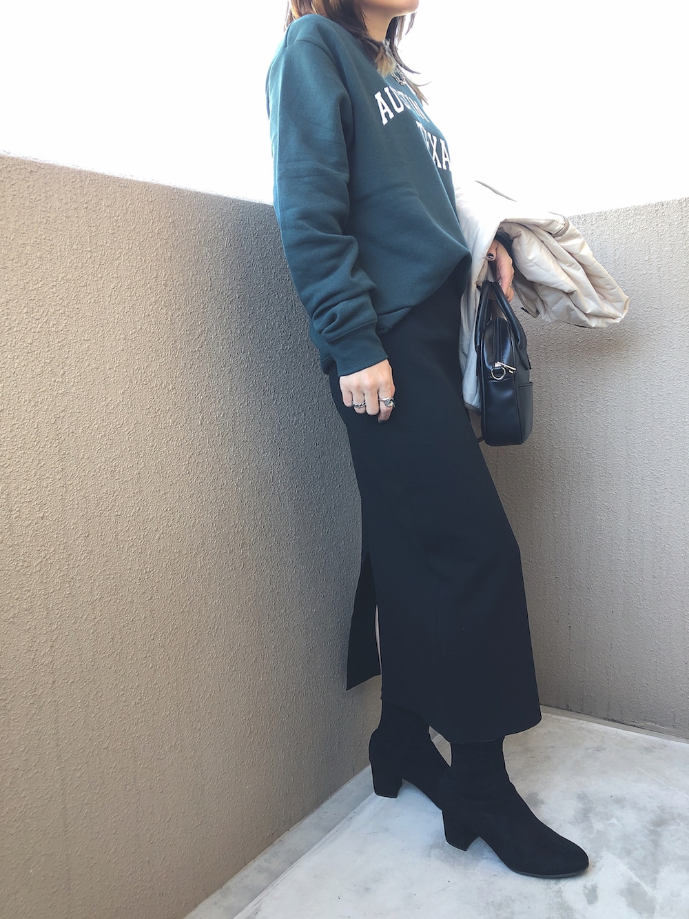 ブラック系のハンドバッグ、ブラック系のブーツ、グリーン系のスウェットを着用したレディースの冬コーディネートの2枚目の写真