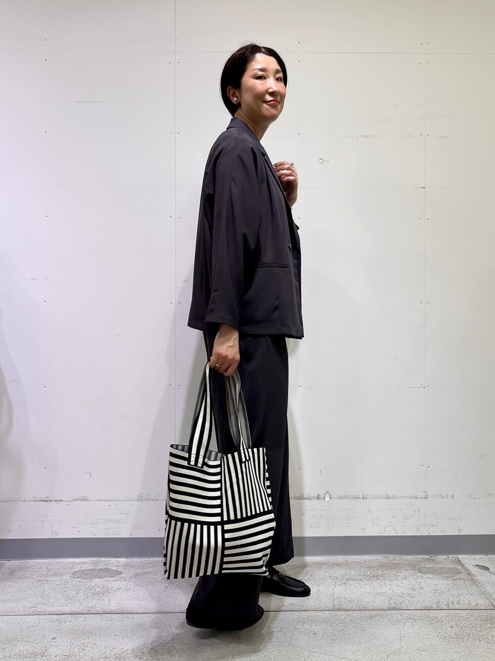 ブラック系のトートバッグ、ホワイト系のTシャツ/カットソー、グレー系のその他パンツを着用したレディースの春コーディネートの3枚目の写真