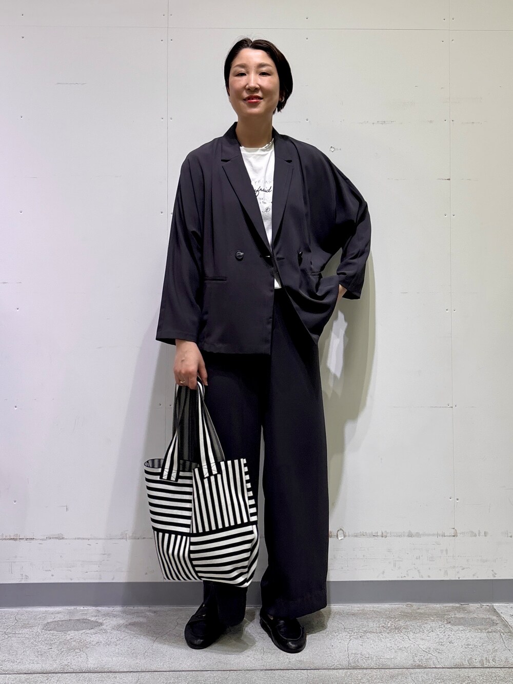 ブラック系のトートバッグ、ホワイト系のTシャツ/カットソー、グレー系のその他パンツを着用したレディースの春コーディネートの2枚目の写真