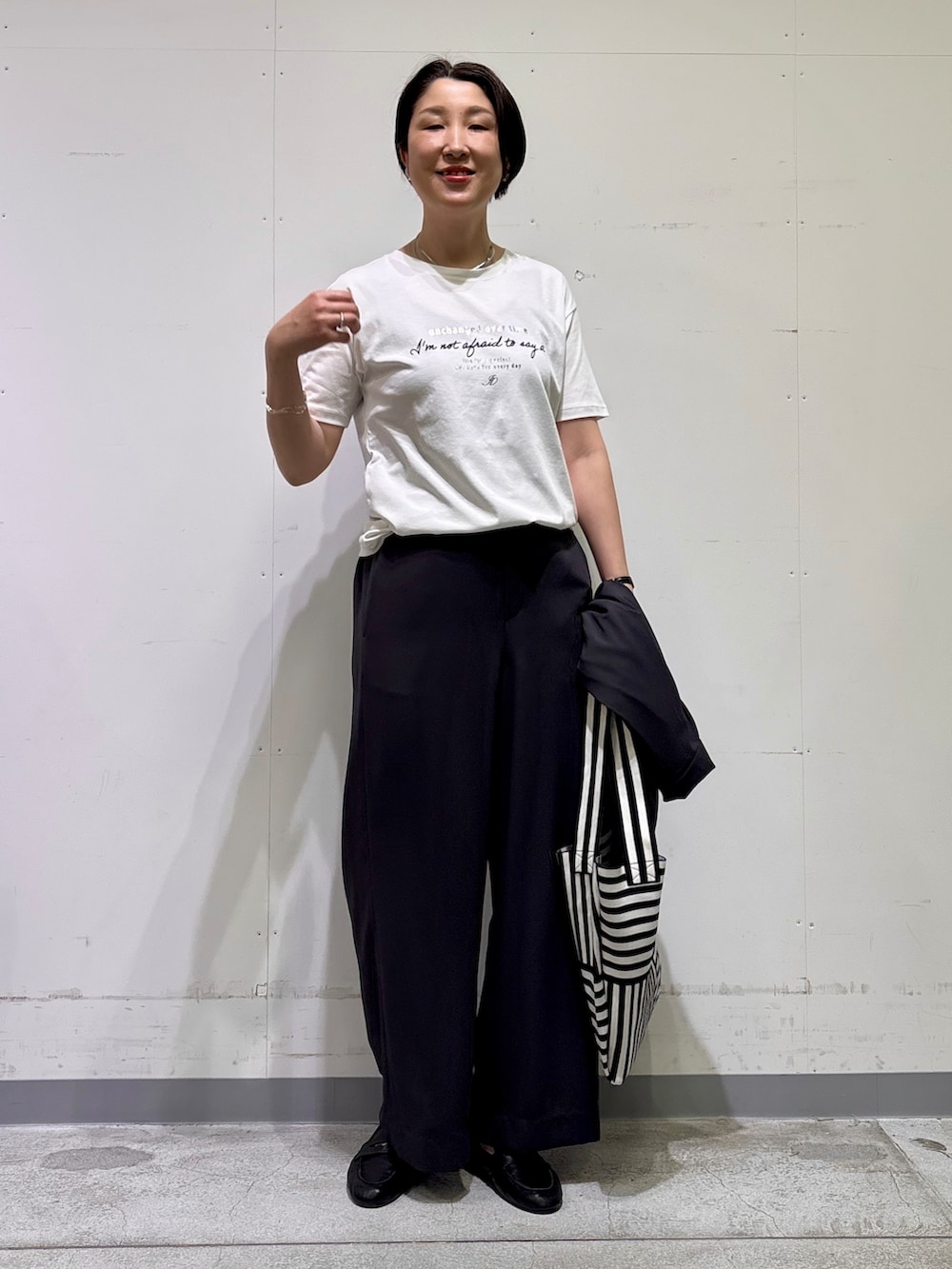 ブラック系のトートバッグ、ホワイト系のTシャツ/カットソー、グレー系のその他パンツを着用したレディースの春コーディネートの9枚目の写真