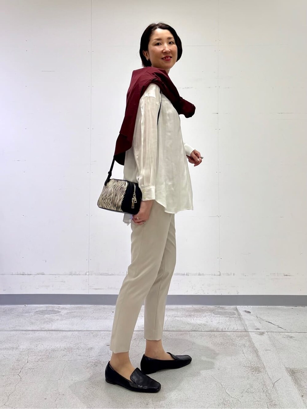 ホワイト系のシャツ/ブラウス、レッド系のニット/セーター、ベージュ系のその他パンツを着用したレディースの春コーディネートの5枚目の写真