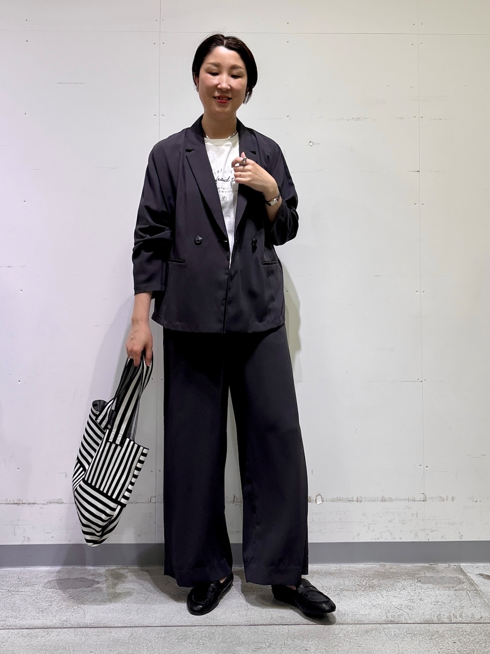ブラック系のトートバッグ、ホワイト系のTシャツ/カットソー、グレー系のその他パンツを着用したレディースの春コーディネートの7枚目の写真
