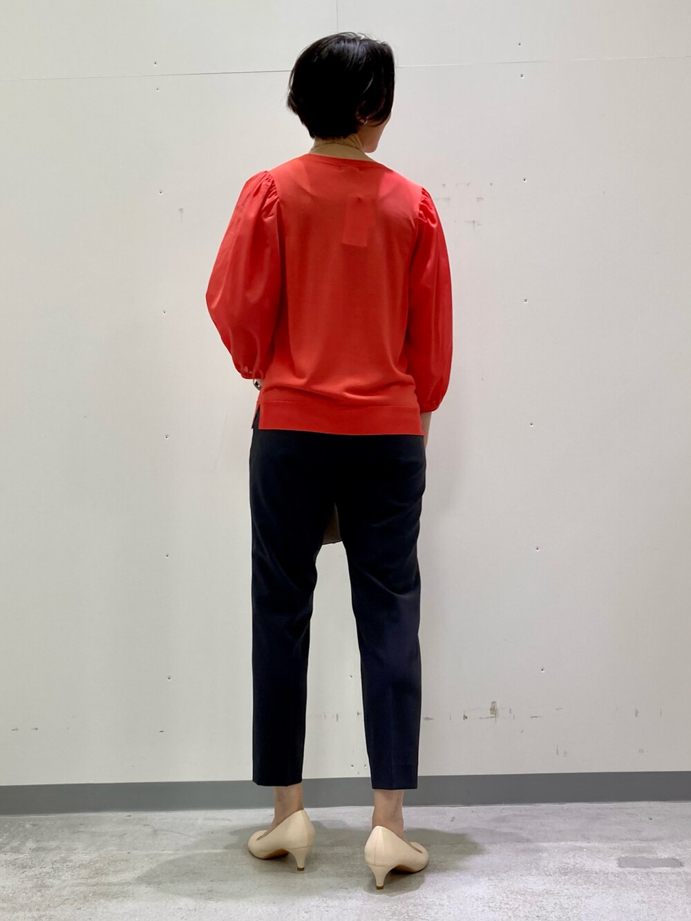 グレー系のスーツパンツ、オレンジ系のニット/セーター、グレー系のスーツジャケットを着用したレディースの秋コーディネートの3枚目の写真