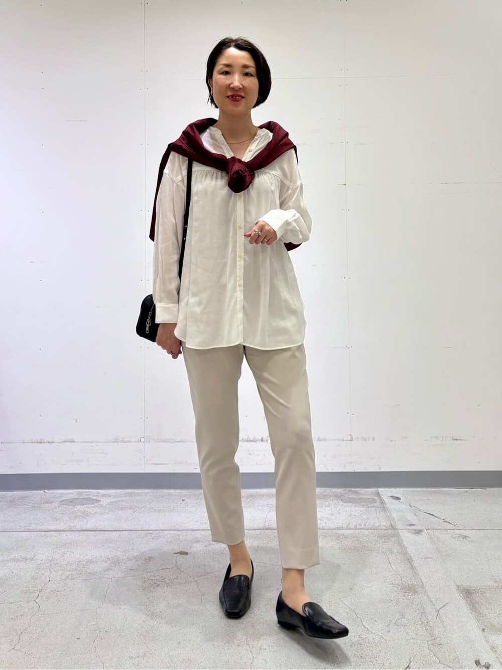 ホワイト系のシャツ/ブラウス、レッド系のニット/セーター、ベージュ系のその他パンツを着用したレディースの春コーディネートの2枚目の写真