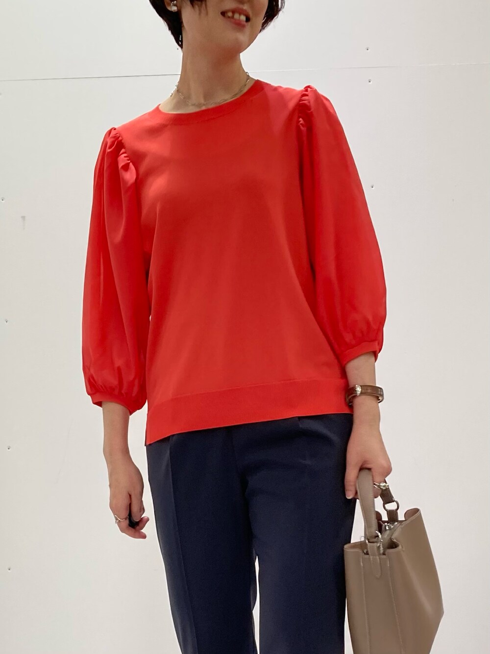 グレー系のスーツパンツ、オレンジ系のニット/セーター、グレー系のスーツジャケットを着用したレディースの秋コーディネートの4枚目の写真