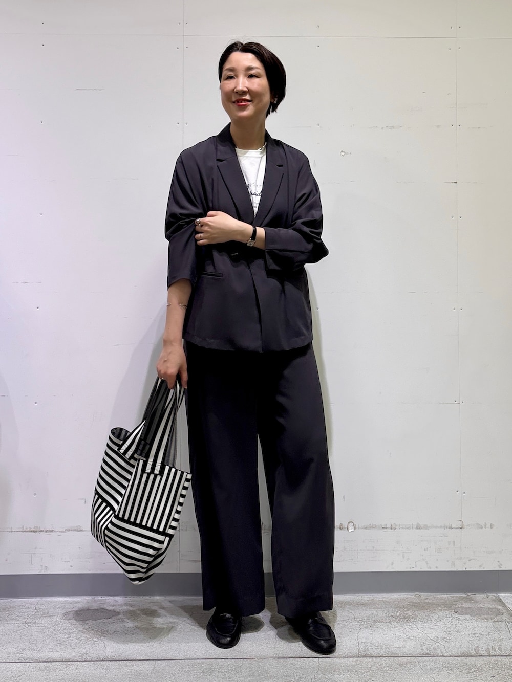 ブラック系のトートバッグ、ホワイト系のTシャツ/カットソー、グレー系のその他パンツを着用したレディースの春コーディネートの6枚目の写真