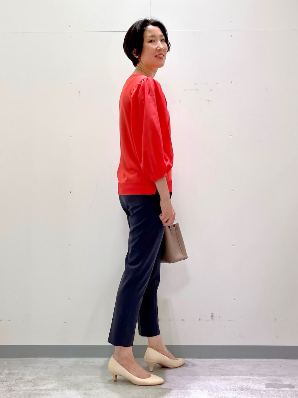 グレー系のスーツパンツ、オレンジ系のニット/セーター、グレー系のスーツジャケットを着用したレディースの秋コーディネートの2枚目の写真