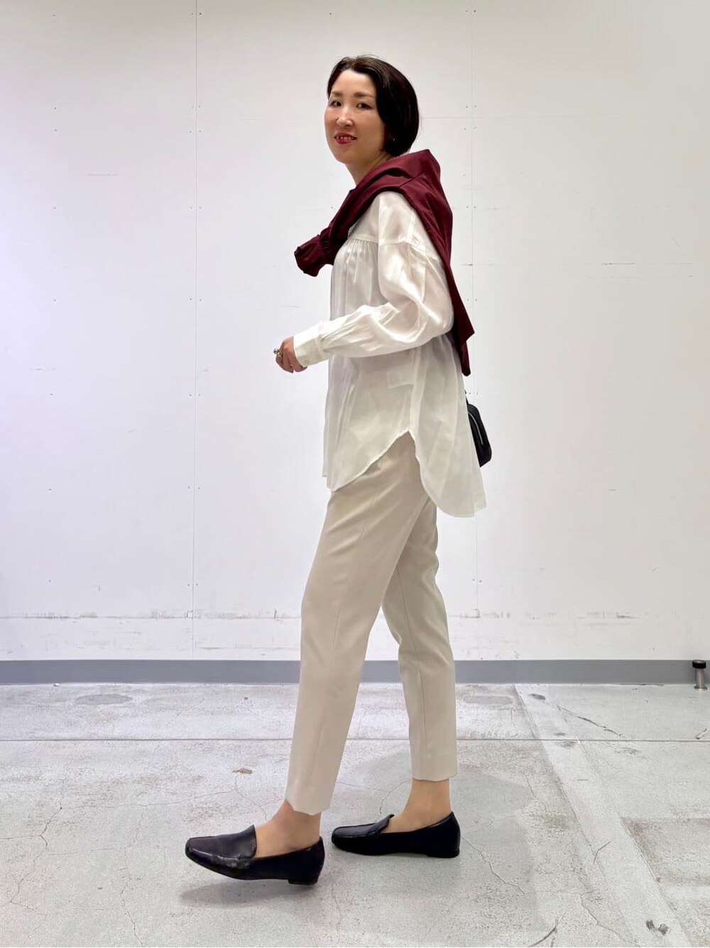 ホワイト系のシャツ/ブラウス、レッド系のニット/セーター、ベージュ系のその他パンツを着用したレディースの春コーディネートの3枚目の写真