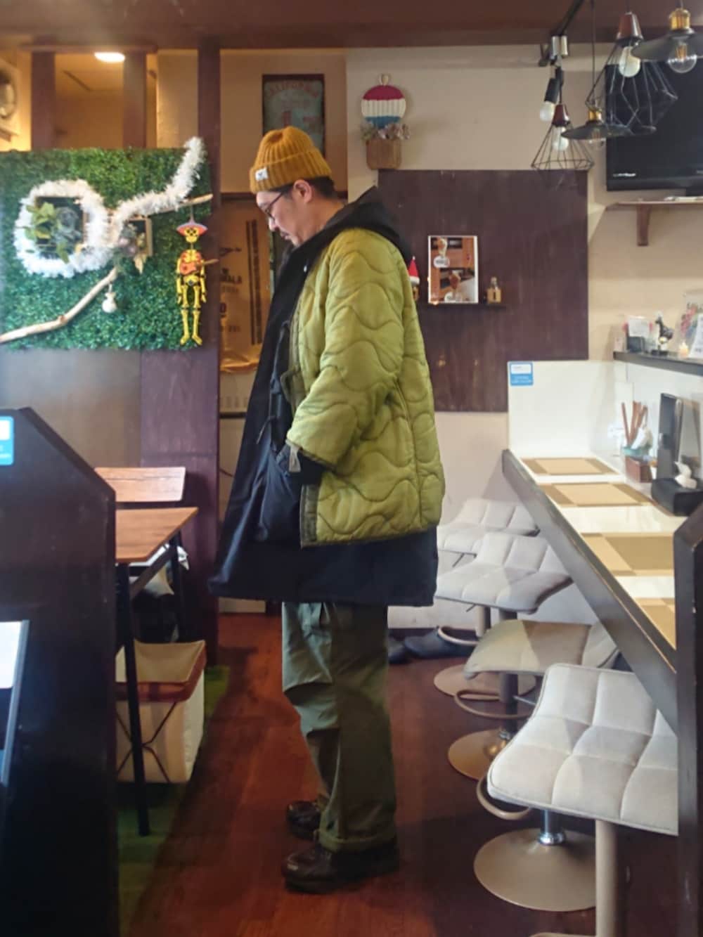 ブラック系のスニーカー、グリーン系のカーゴパンツ、ブラック系のモッズコートを着用したメンズの秋コーディネートの2枚目の写真