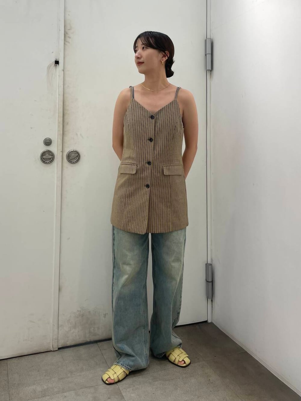 ブラウン系のチュニック、ブルー系のデニムパンツ、ゴールド系のネックレスを着用したレディースの夏コーディネートの2枚目の写真