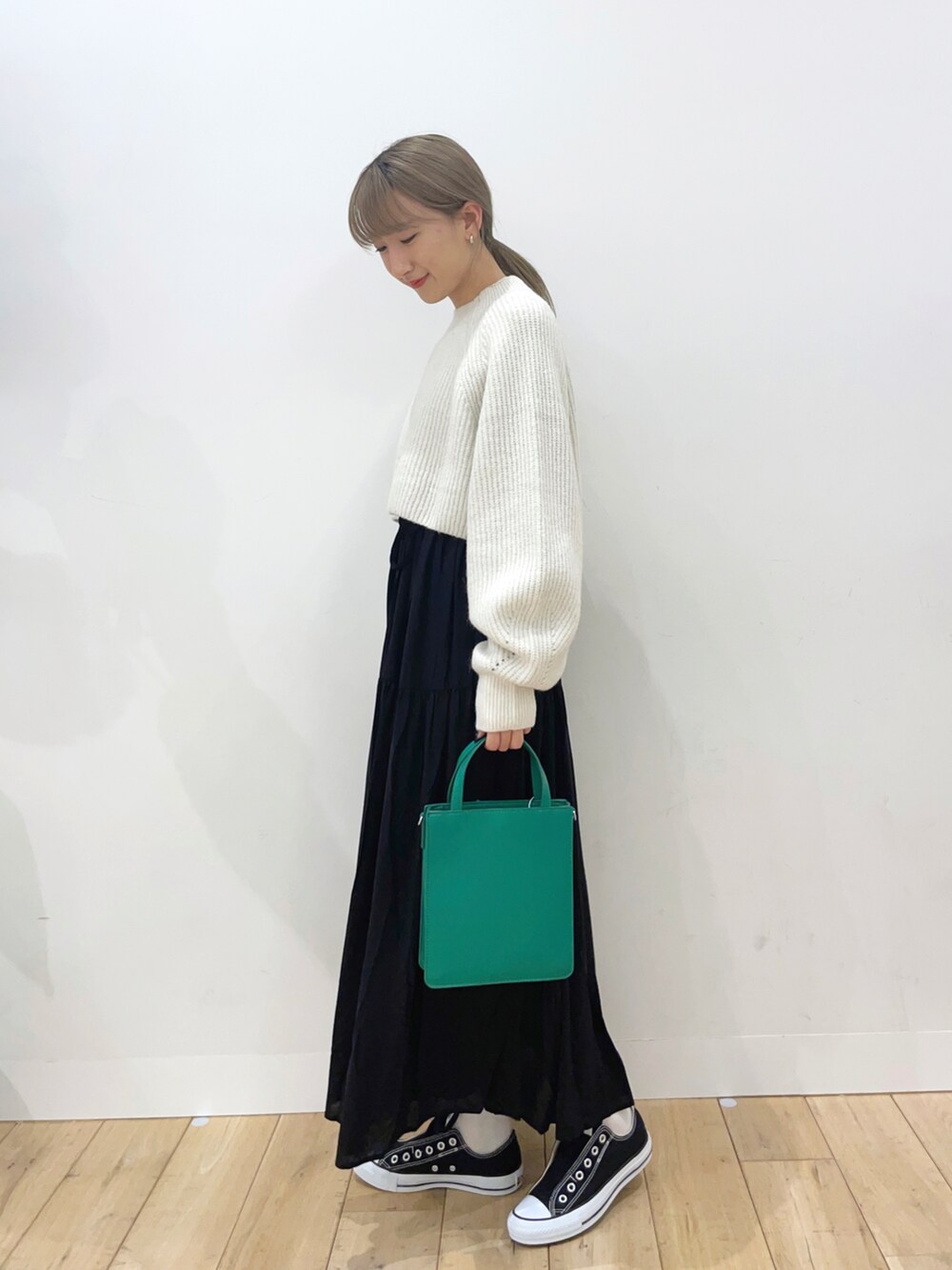ホワイト系のニット/セーター、ブラック系のワンピース、グリーン系のショルダーバッグを着用したレディースの冬コーディネートの2枚目の写真