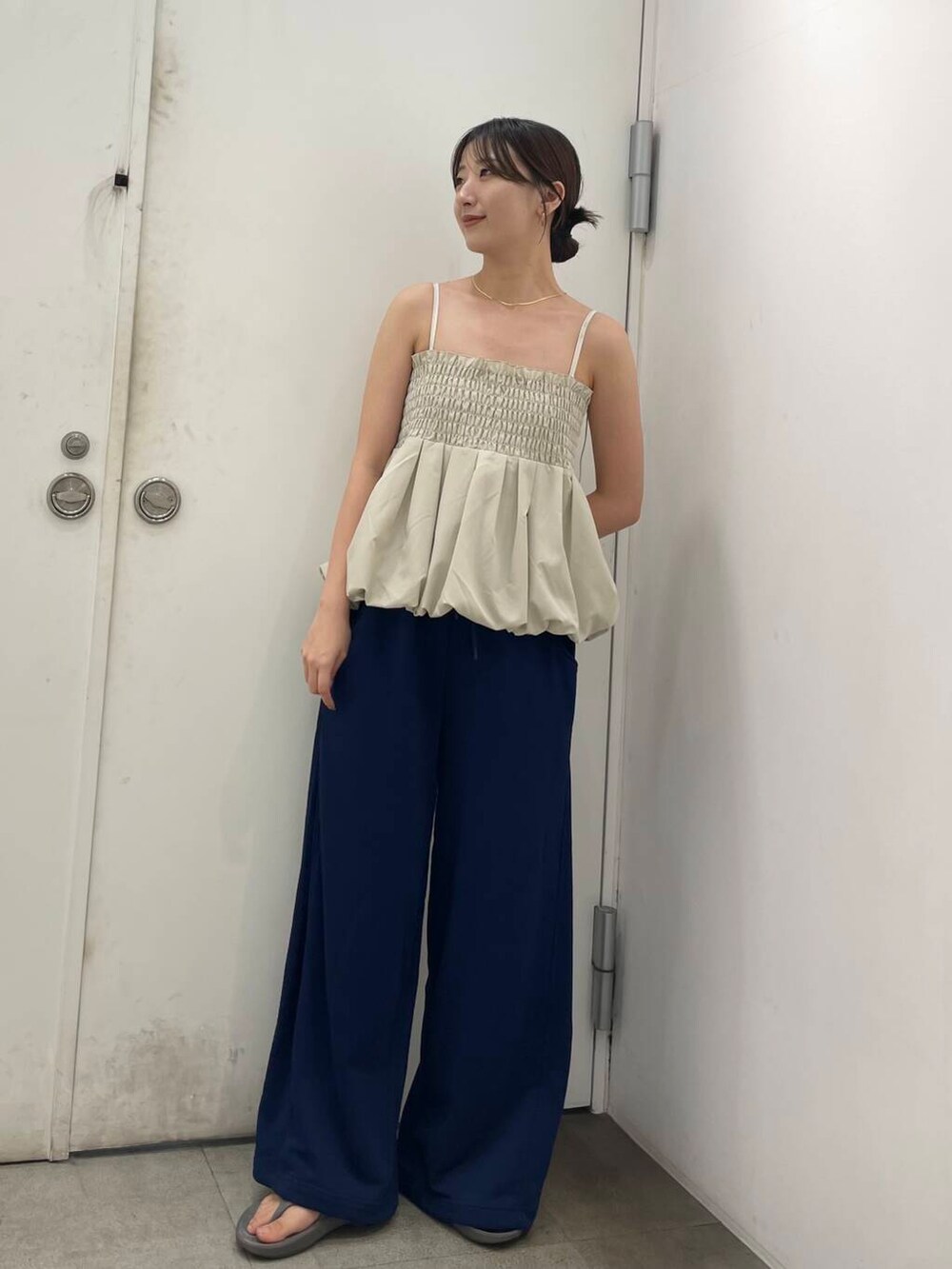 ブルー系のスウェットパンツ、ベージュ系のベスト、シルバー系のピアス(両耳用)を着用したレディースの秋コーディネートの2枚目の写真