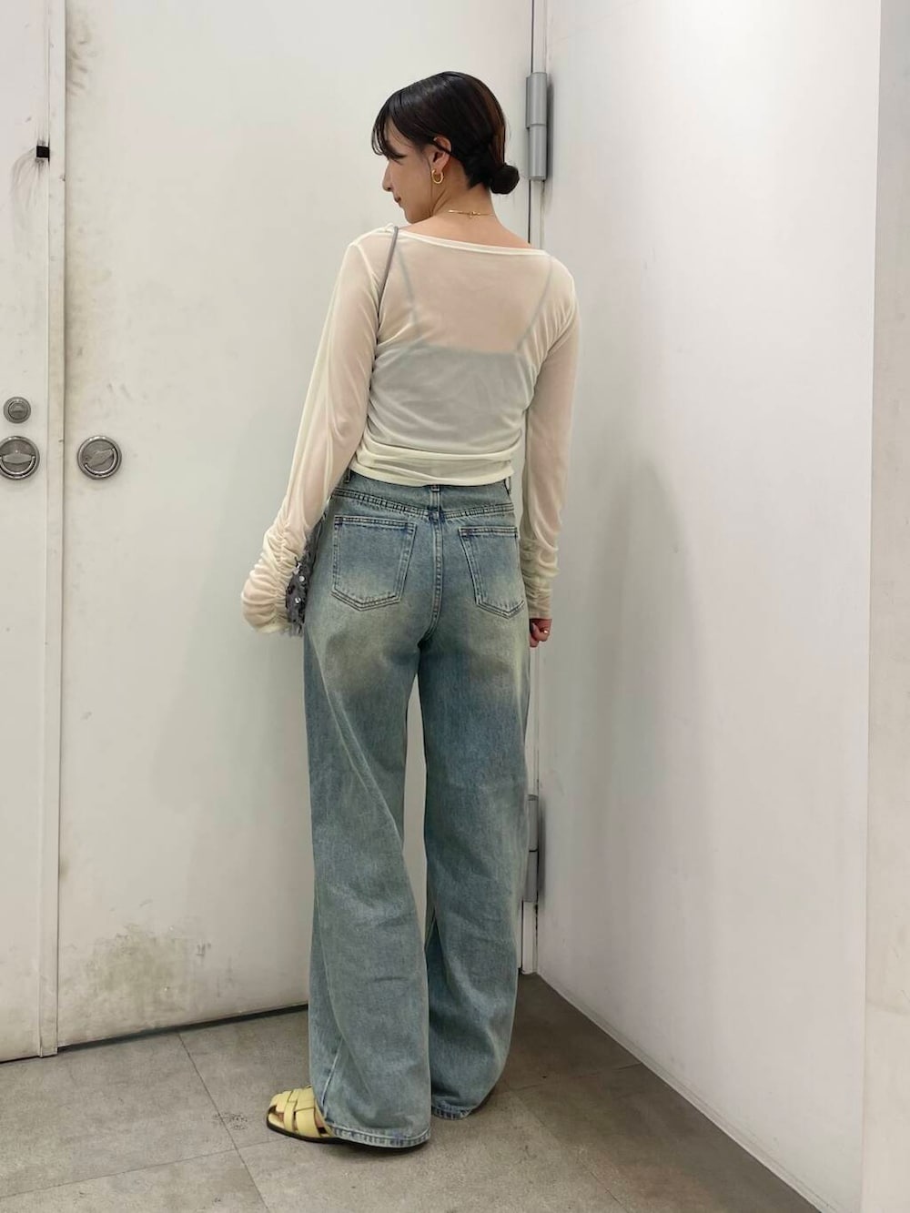 グレー系のハンドバッグ、ベージュ系のその他トップス、ブルー系のデニムパンツを着用したレディースの夏コーディネートの2枚目の写真