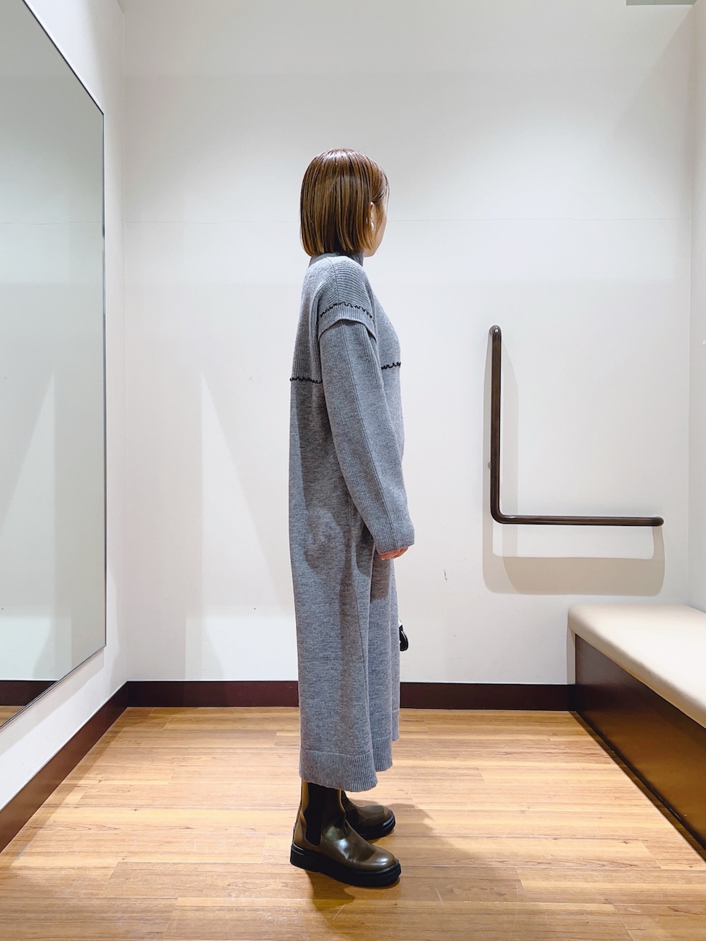 グレー系のワンピース、ブラウン系のブーツ、ベージュ系のハンドバッグを着用したレディースの冬コーディネートの3枚目の写真