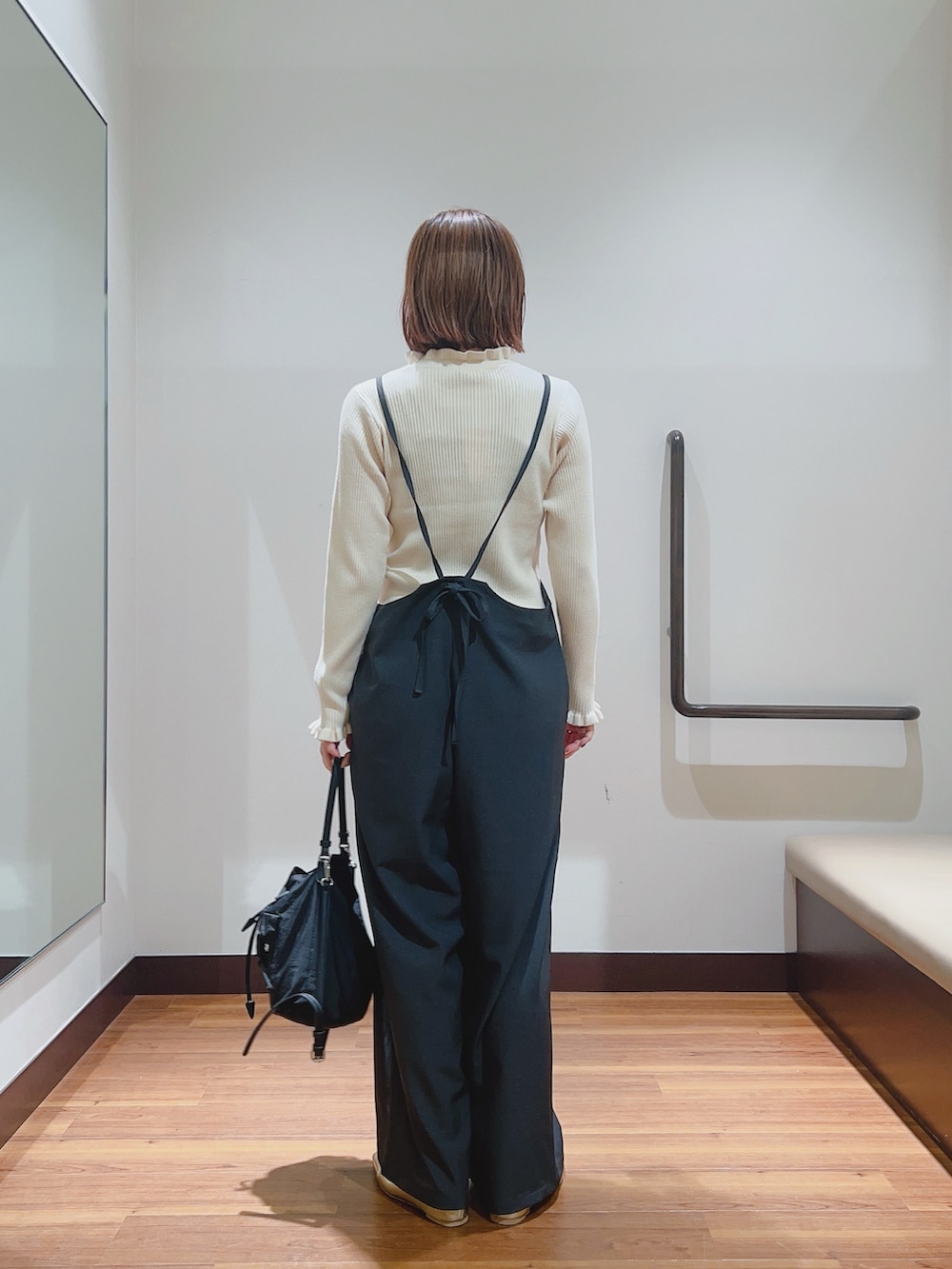 グレー系のサロペット/オーバーオール、ホワイト系のニット/セーター、ブラック系のハンドバッグを着用したレディースの秋コーディネートの3枚目の写真
