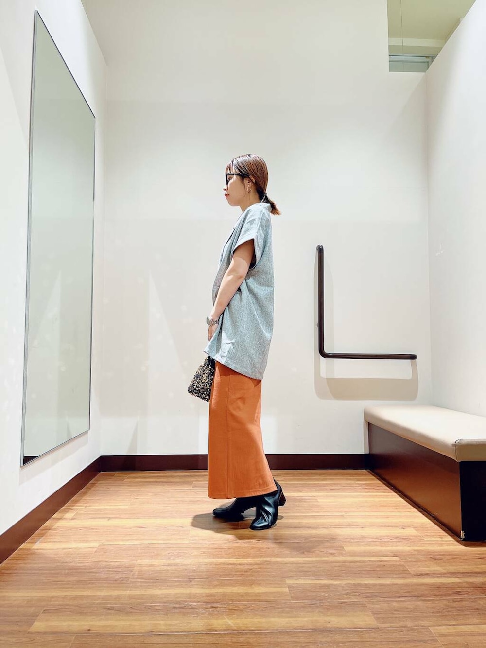 ブラック系のブーツ、ゴールド系のショルダーバッグ、オレンジ系のスカートを着用したレディースの秋コーディネートの3枚目の写真