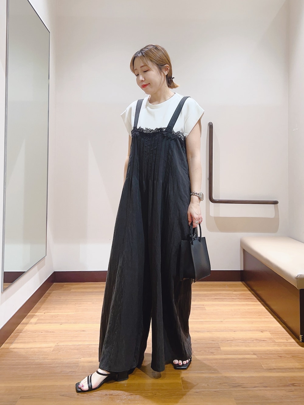 ホワイト系のハンドバッグ、ホワイト系のTシャツ/カットソー、ブラック系のその他パンツを着用したレディースの夏コーディネートの2枚目の写真