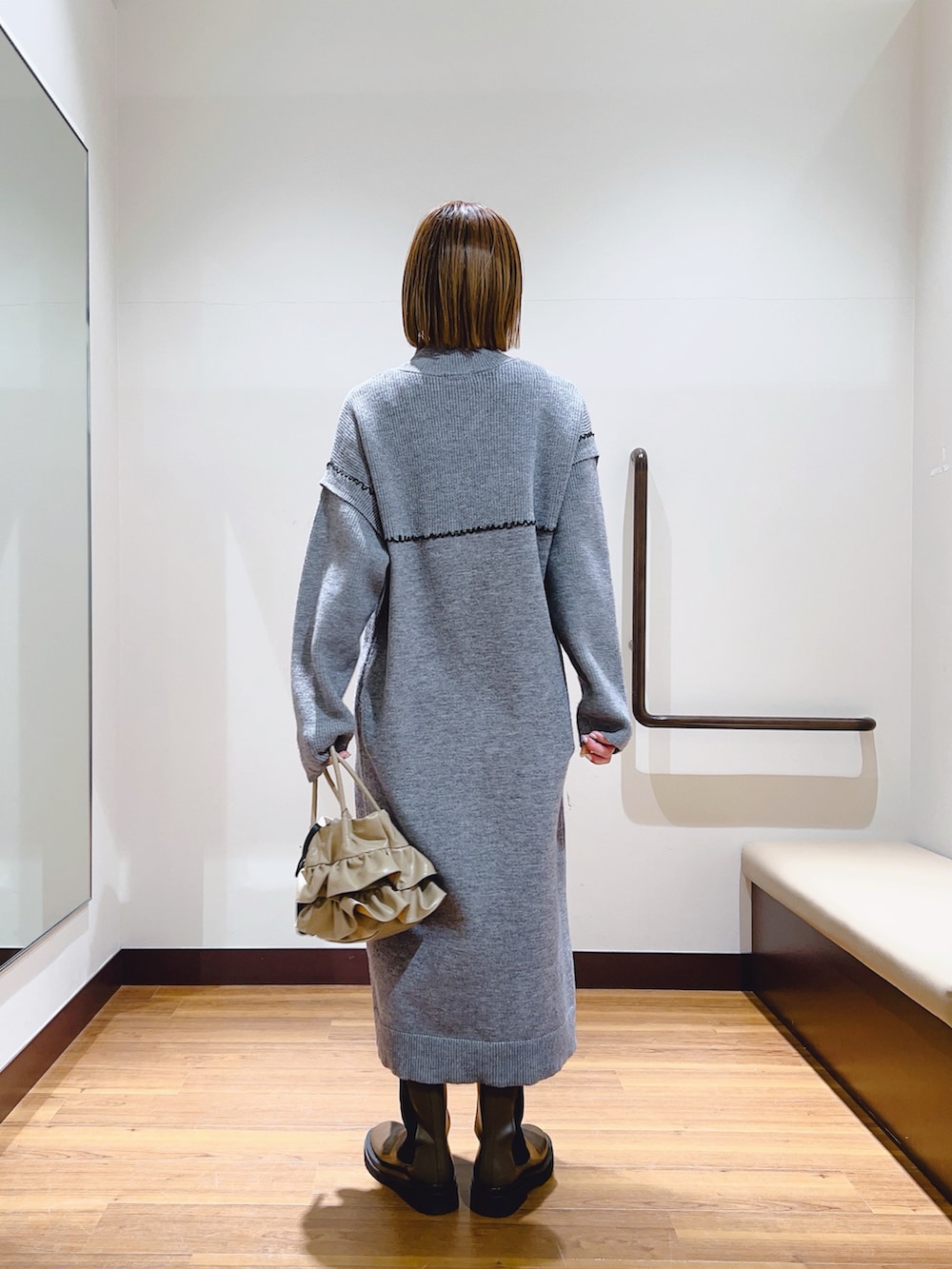 グレー系のワンピース、ブラウン系のブーツ、ベージュ系のハンドバッグを着用したレディースの冬コーディネートの2枚目の写真