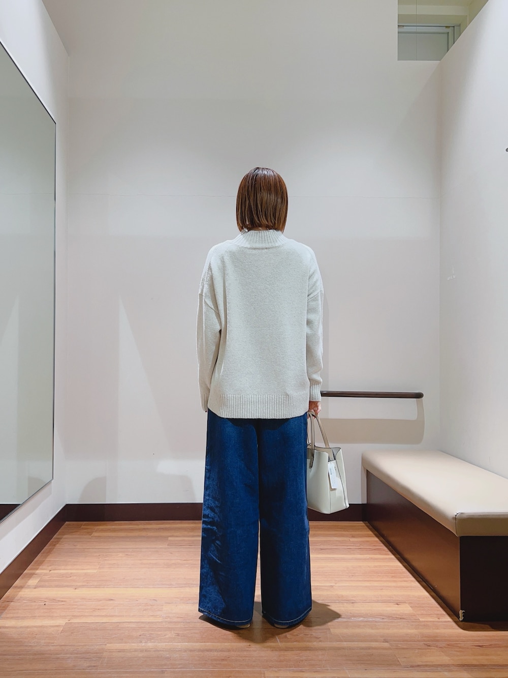 ホワイト系のニット/セーター、ブルー系のデニムパンツ、ホワイト系のトートバッグを着用したレディースの冬コーディネートの4枚目の写真