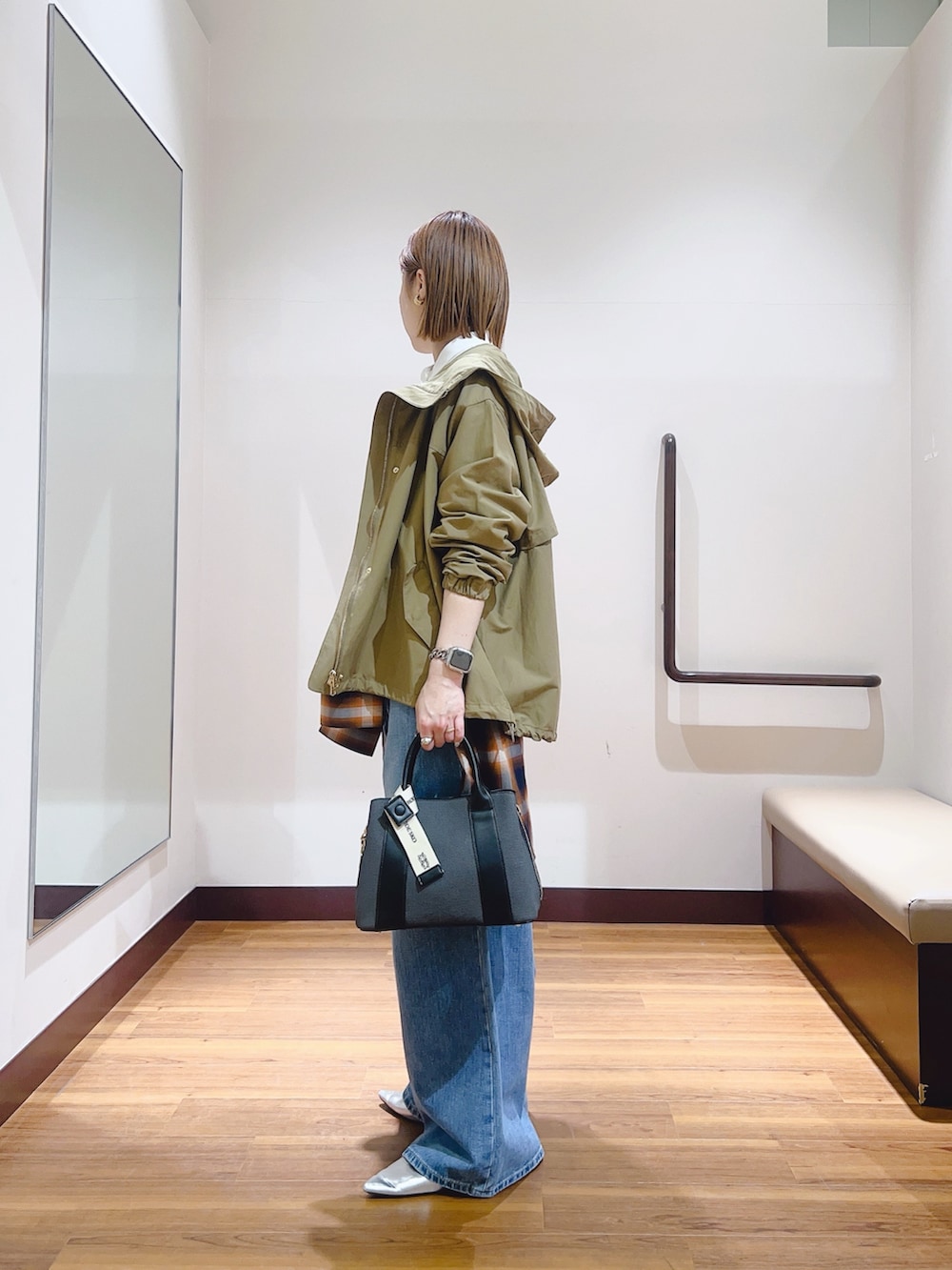 ブルー系のデニムパンツ、ブラック系のハンドバッグ、ホワイト系のマウンテンパーカーを着用したレディースの春コーディネートの4枚目の写真