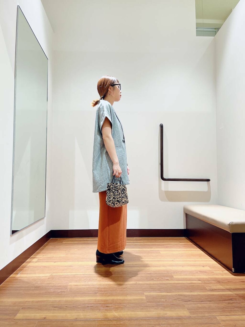 ブラック系のブーツ、ゴールド系のショルダーバッグ、オレンジ系のスカートを着用したレディースの秋コーディネートの2枚目の写真