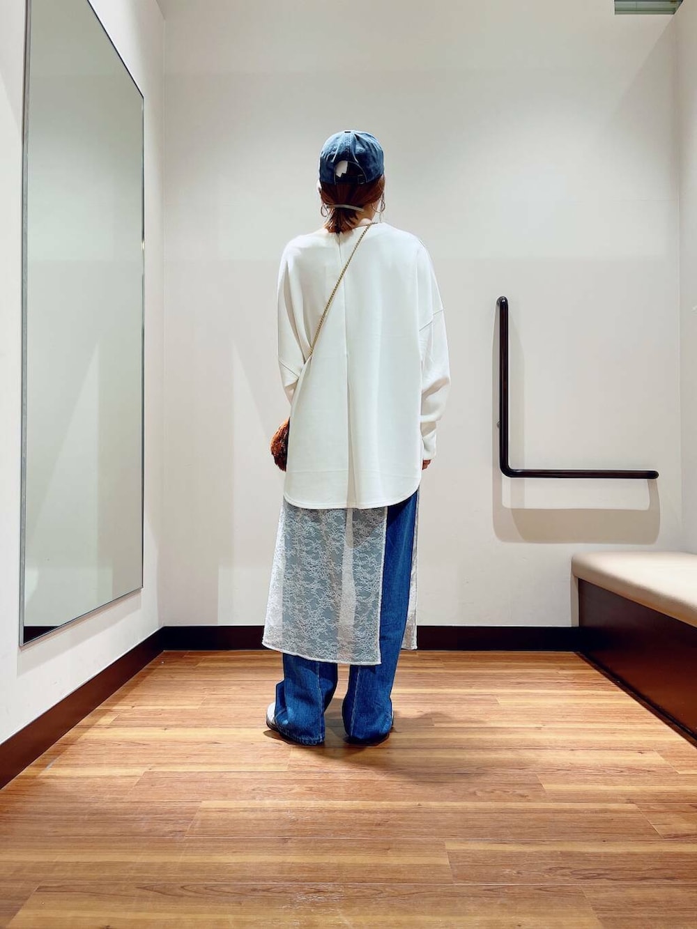 ブラウン系のショルダーバッグ、ブルー系のデニムパンツ、ホワイト系のスカートを着用したレディースの秋コーディネートの4枚目の写真