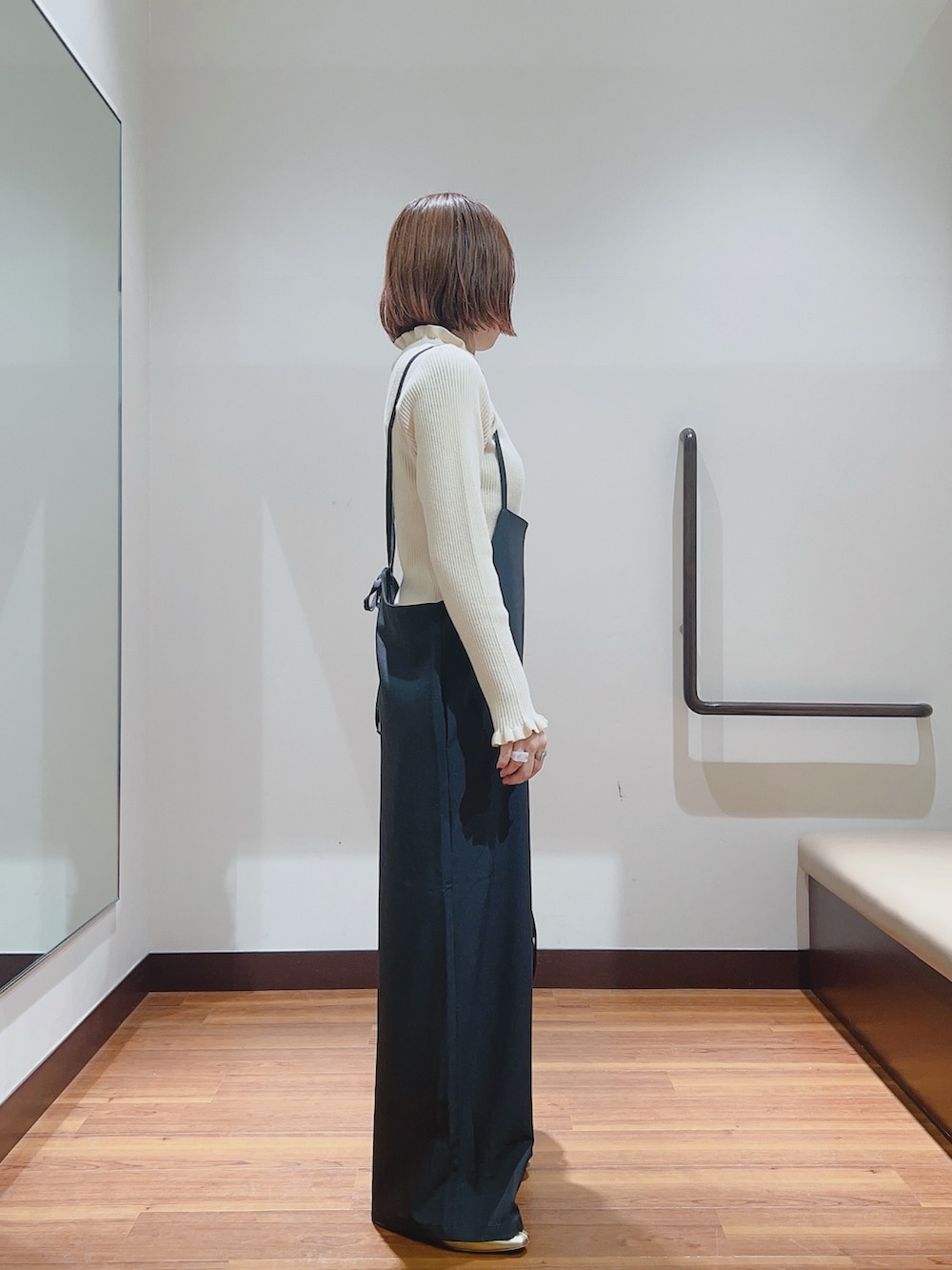 グレー系のサロペット/オーバーオール、ホワイト系のニット/セーター、ブラック系のハンドバッグを着用したレディースの秋コーディネートの2枚目の写真