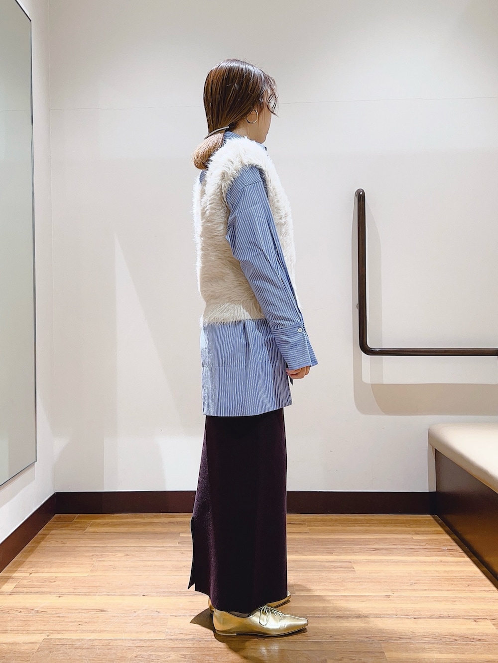 ブルー系のTシャツ/カットソー、グレー系のベスト、ブラウン系のスカートを着用したレディースの冬コーディネートの4枚目の写真