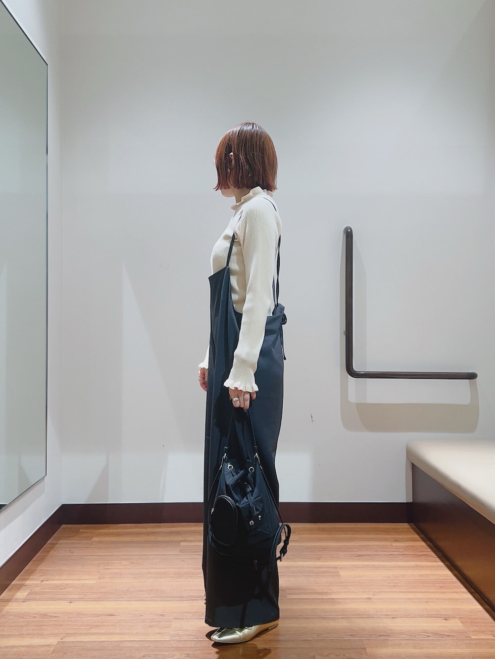 グレー系のサロペット/オーバーオール、ホワイト系のニット/セーター、ブラック系のハンドバッグを着用したレディースの秋コーディネートの4枚目の写真