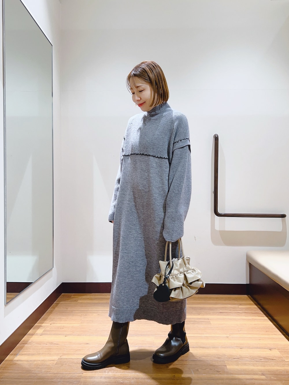 グレー系のワンピース、ブラウン系のブーツ、ベージュ系のハンドバッグを着用したレディースの冬コーディネートの4枚目の写真