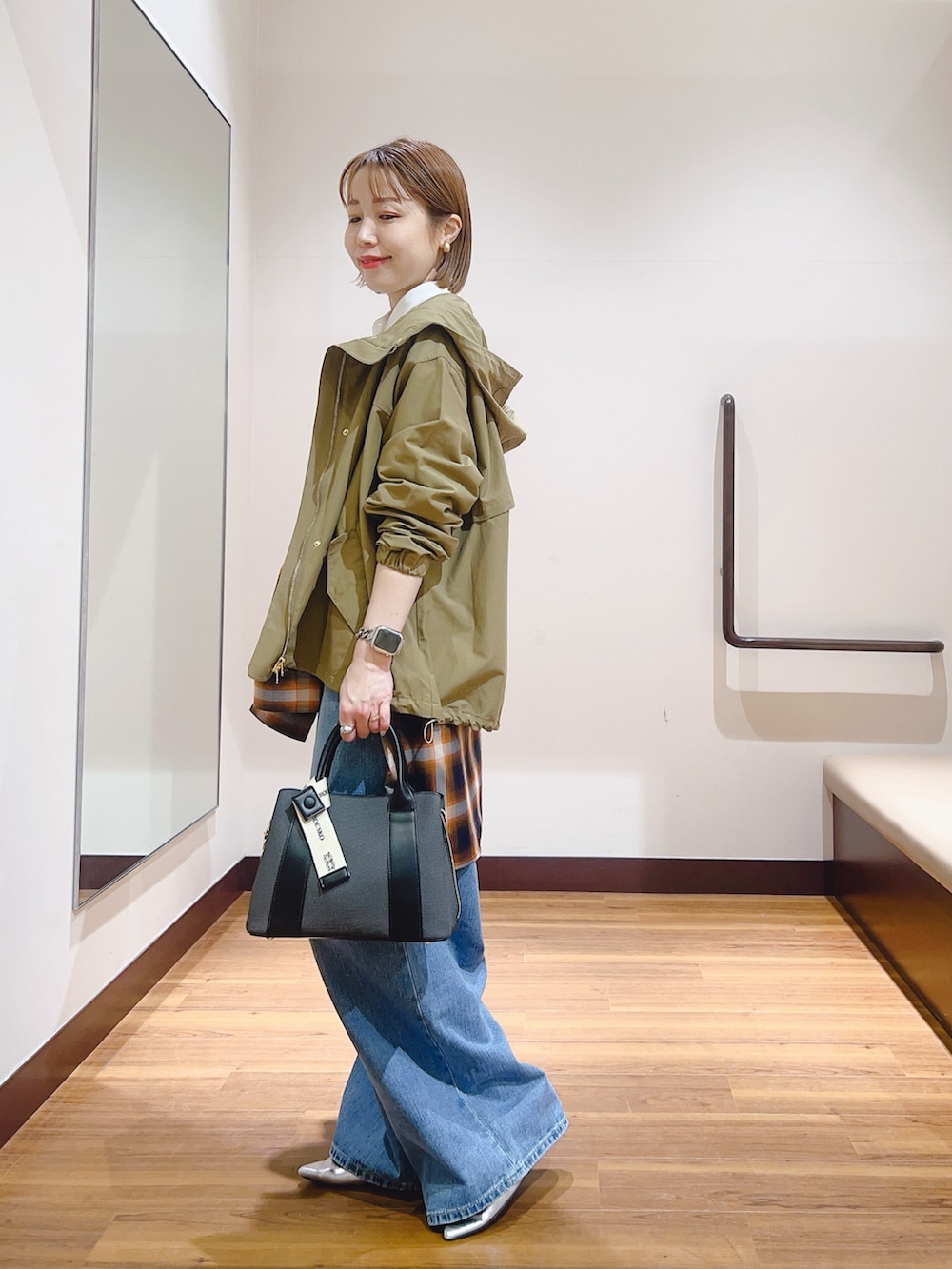 ブルー系のデニムパンツ、ブラック系のハンドバッグ、ホワイト系のマウンテンパーカーを着用したレディースの春コーディネートの2枚目の写真