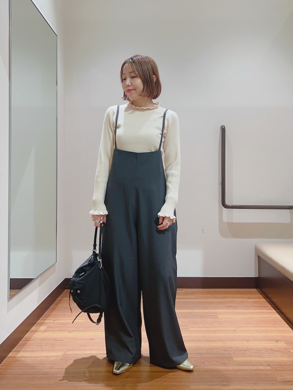 グレー系のサロペット/オーバーオール、ホワイト系のニット/セーター、ブラック系のハンドバッグを着用したレディースの秋コーディネートの5枚目の写真