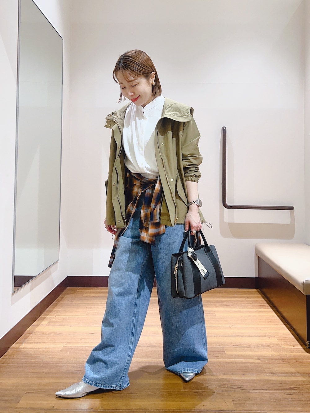 ブルー系のデニムパンツ、ブラック系のハンドバッグ、ホワイト系のマウンテンパーカーを着用したレディースの春コーディネートの3枚目の写真