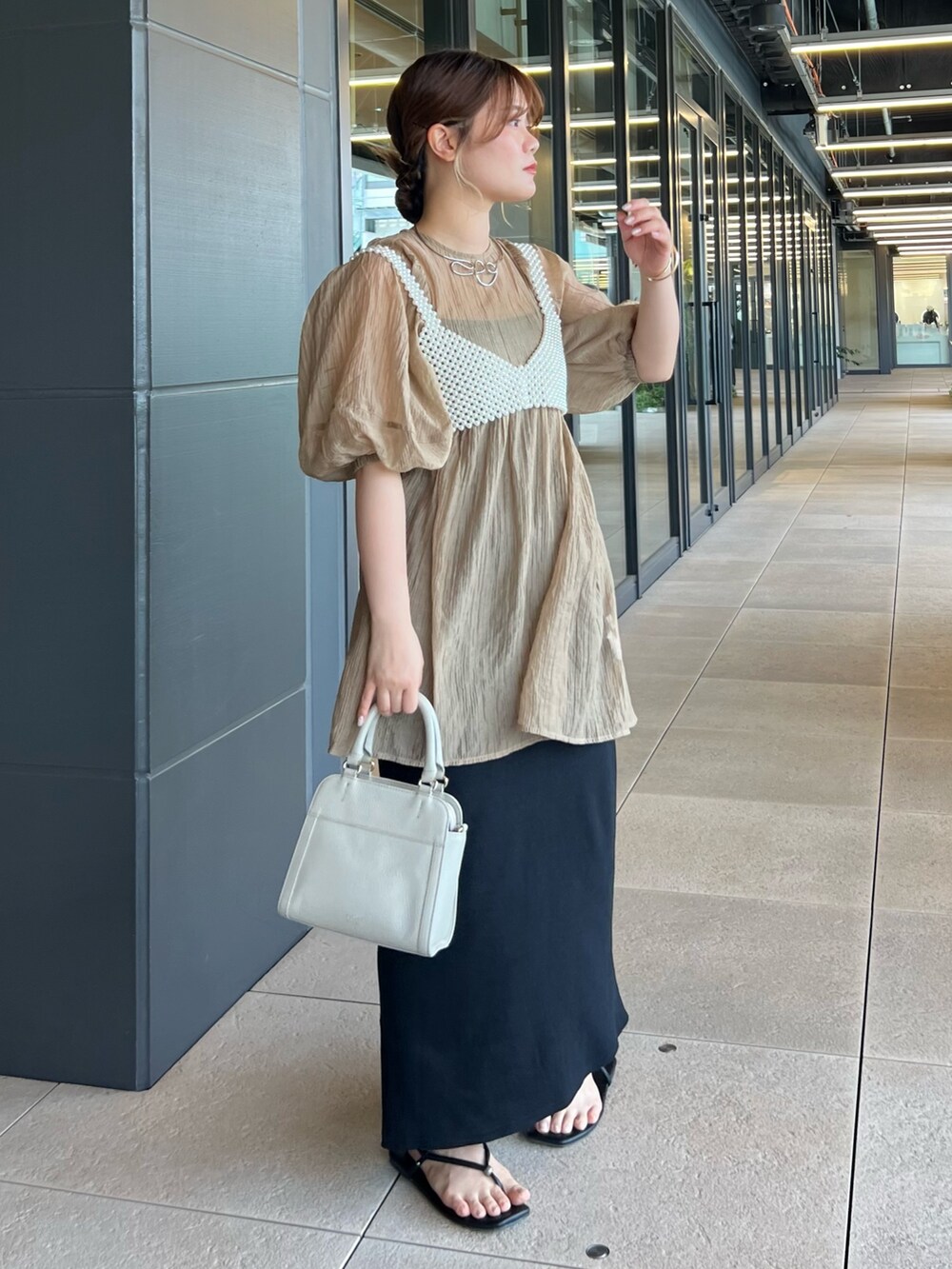 ベージュ系のシャツ/ブラウス、ホワイト系のベスト、ブラック系のワンピースを着用したレディースの春コーディネートの2枚目の写真