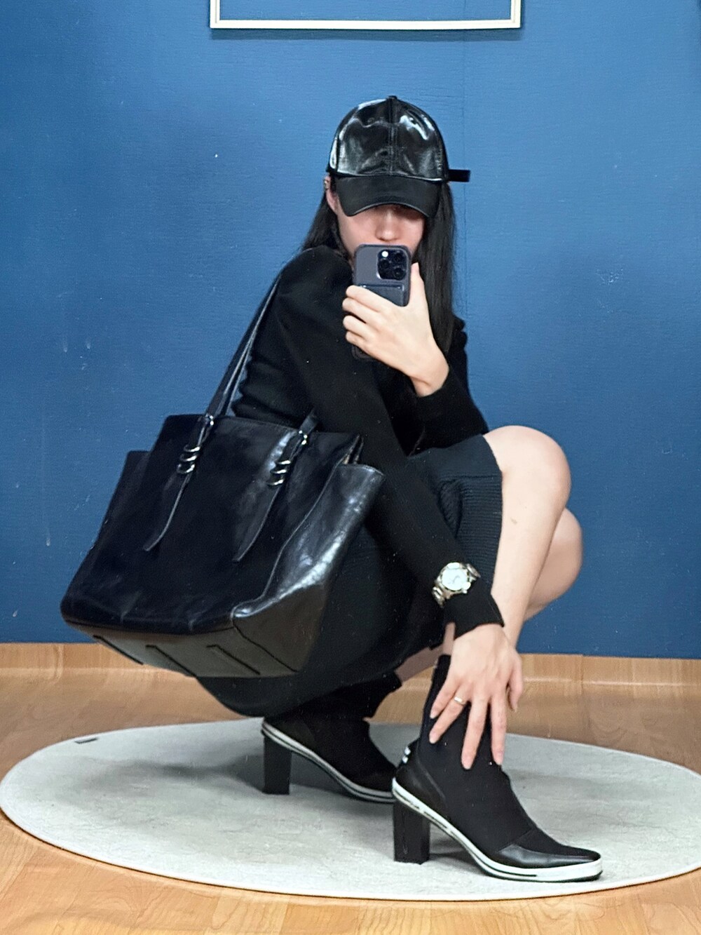 ブラック系のショルダーバッグ、ブラック系のブーティ、ブラック系のキャップを着用したレディースの秋コーディネートの3枚目の写真