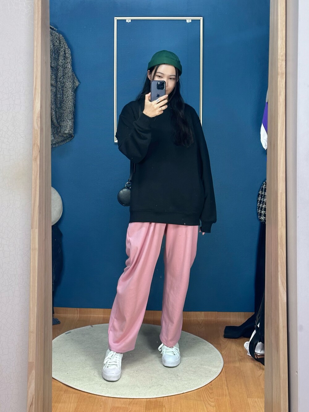 ブラック系のショルダーバッグ、ホワイト系のスニーカー、グリーン系の帽子を着用したレディースの秋コーディネートの2枚目の写真