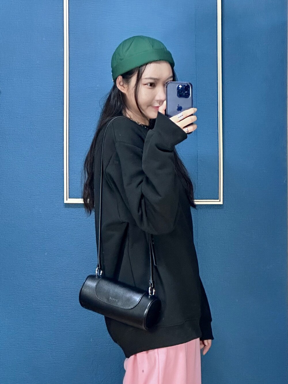 ブラック系のショルダーバッグ、ホワイト系のスニーカー、グリーン系の帽子を着用したレディースの秋コーディネートの3枚目の写真