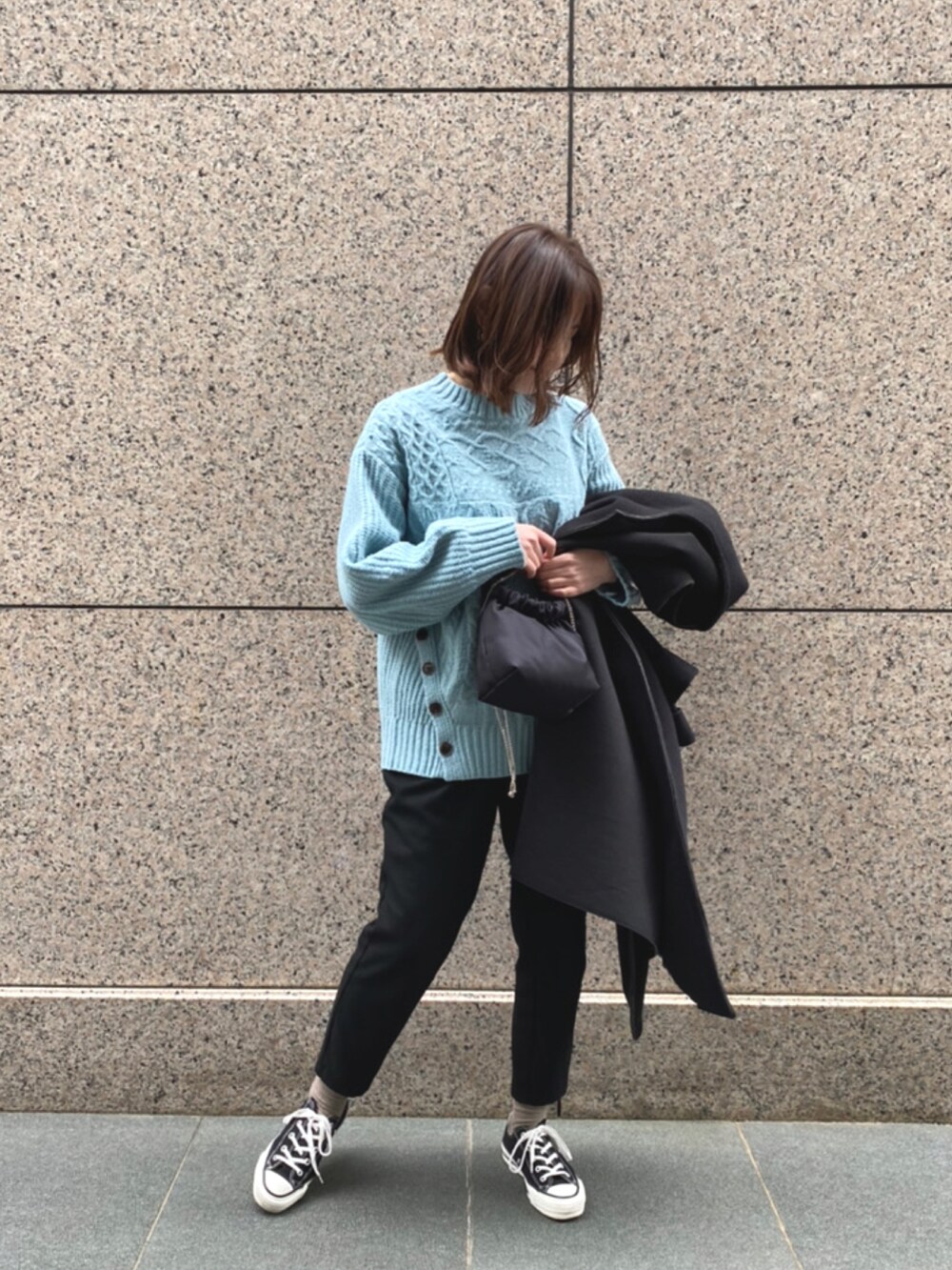 ブルー系のニット/セーター、ブラック系のノーカラーコートを着用したレディースの冬コーディネートの2枚目の写真